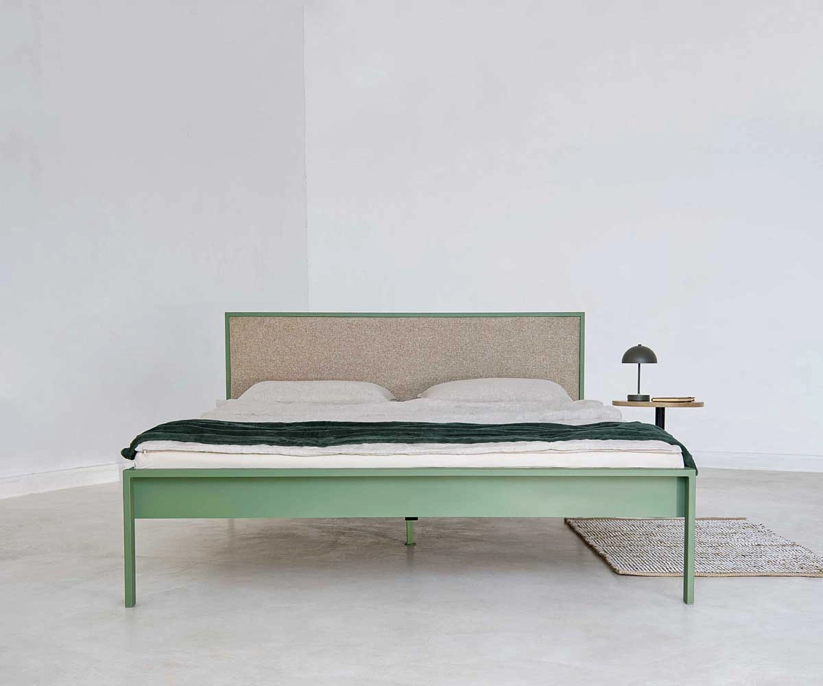 Side view of green metal bed with beige upholstered headboard Side view of a modern green metal bed with beige upholstered headboard without footboard